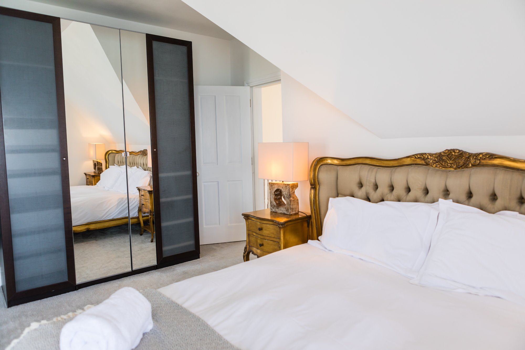Bedroom with ornate gold headboard and mirrored wardrobes